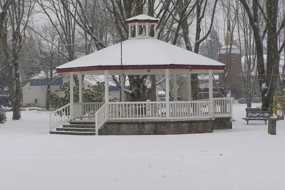 White gazebo in Wait Park covered in fresh snow among bare trees in Canby, Oregon