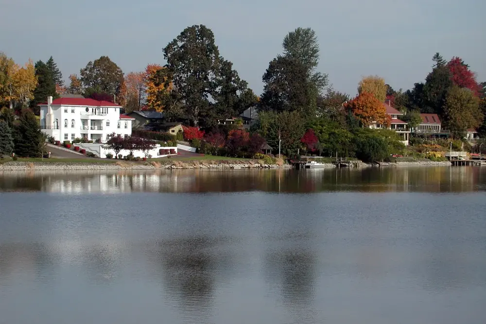 Fairview Lake with autumn trees and lakeside homes reflected in still water in Fairview, Oregon