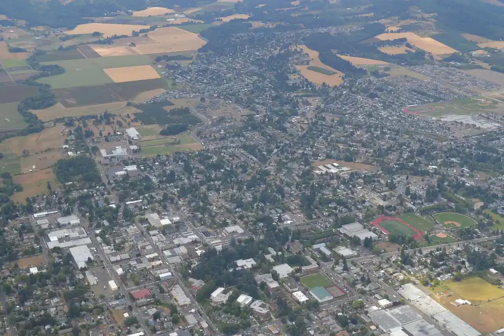 Aerial view of Forest Grove, Oregon, with tree-lined neighborhoods surrounded by farm fields