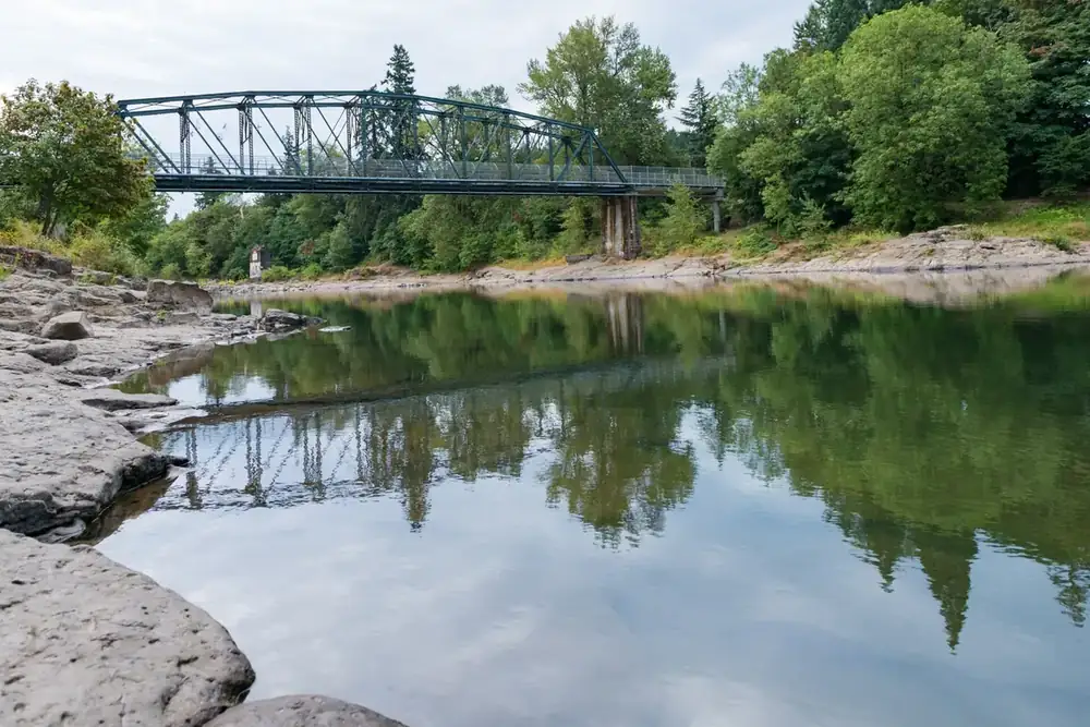 Clackamas River reflecting a steel truss bridge and riverside trees at Cross Park in Gladstone