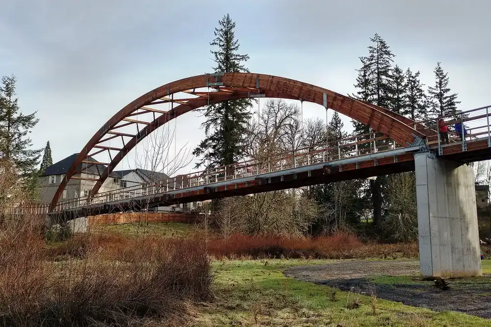 Arched timber footbridge over wetland grasses in Orenco Woods Nature Park, Hillsboro, Oregon