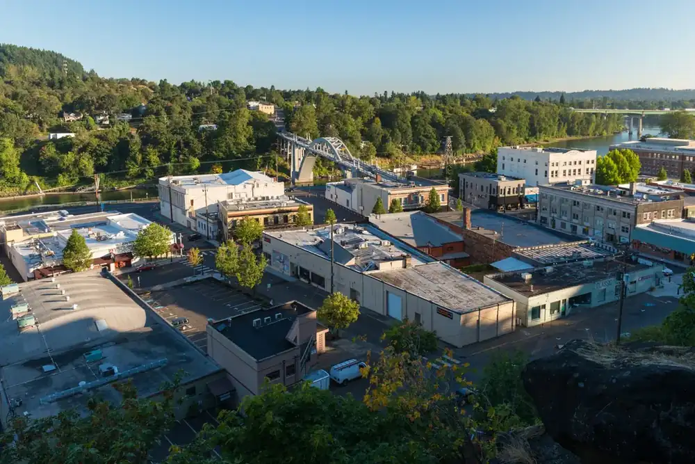 Downtown Oregon City rooftops seen from the bluff, with the Willamette River and arch bridge
