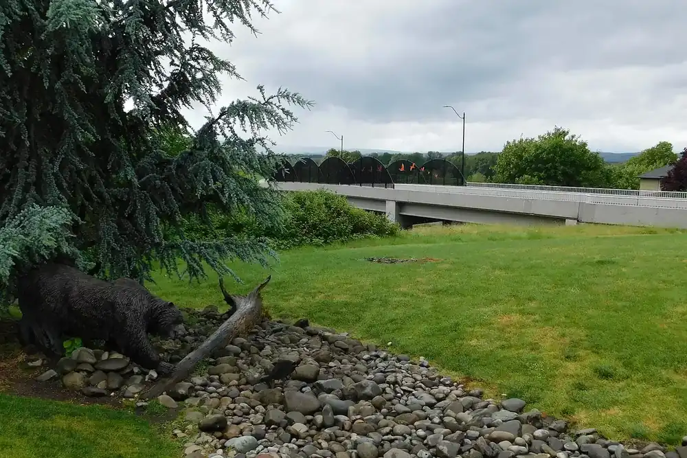 Grassy Overlook Park with a bear sculpture beside the Pioneer Street bridge in Ridgefield, Washington