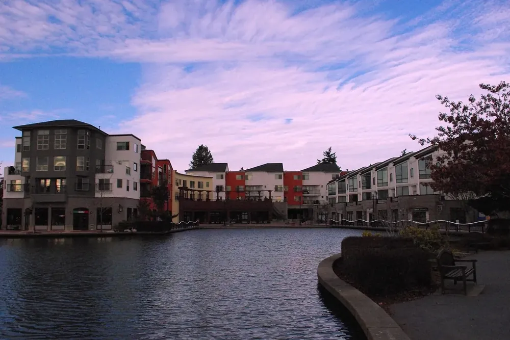 Apartments and townhomes around the lake at Tualatin Commons under an evening sky in Oregon
