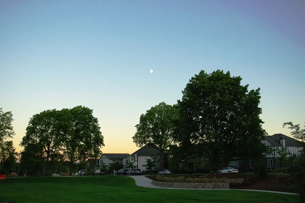 Palermo Park lawn and shade trees at dusk beside townhouses in Wilsonville, Oregon